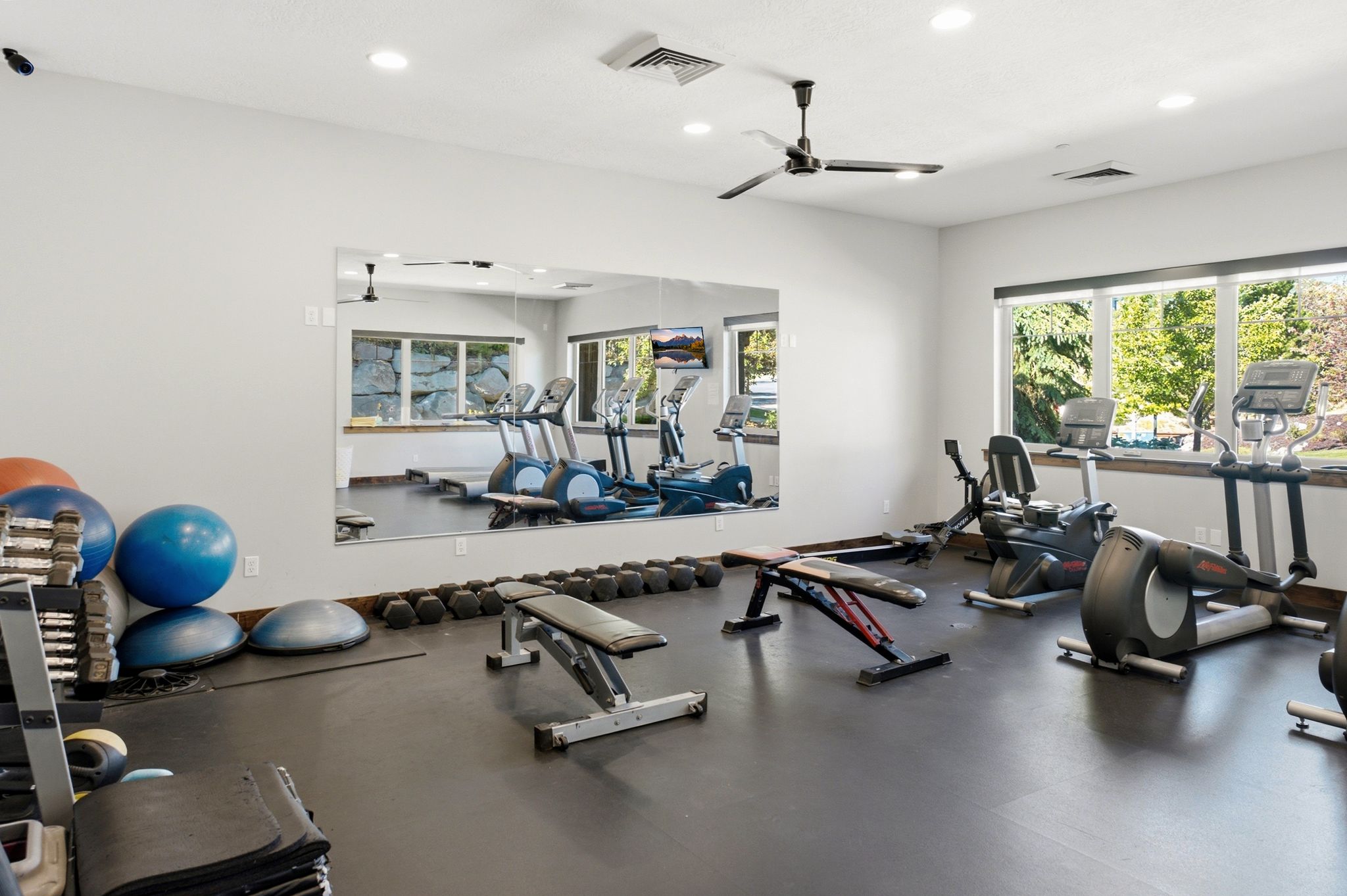 Dedicated fitness space featuring a rubberized floor, full-wall mirror, recessed lighting, and a ceiling fan