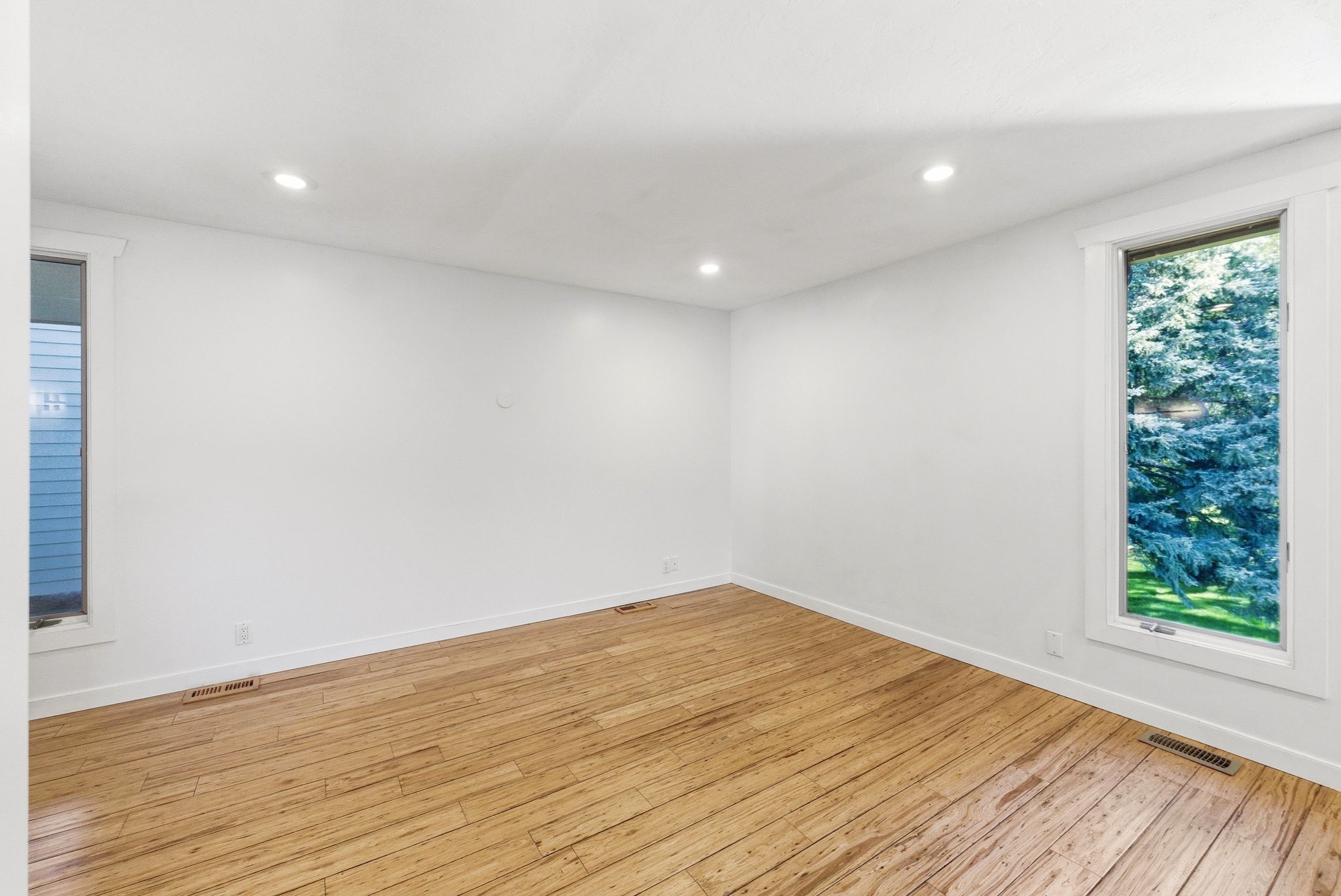 Bright room featuring wood-finish flooring, recessed lighting, and white trim
