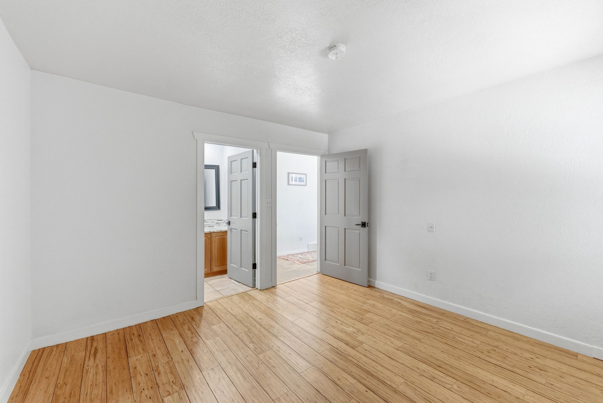 Room featuring wood-finish flooring, white walls, and white baseboards