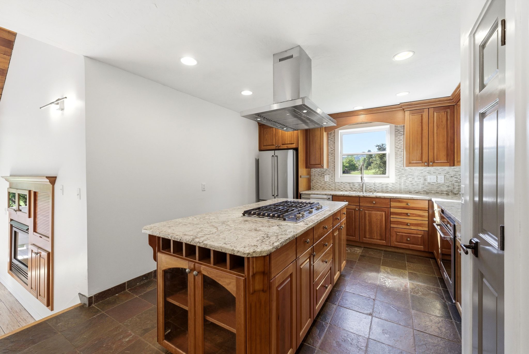Kitchen featuring a large central island with a gas cooktop, stone countertop, and integrated wine storage