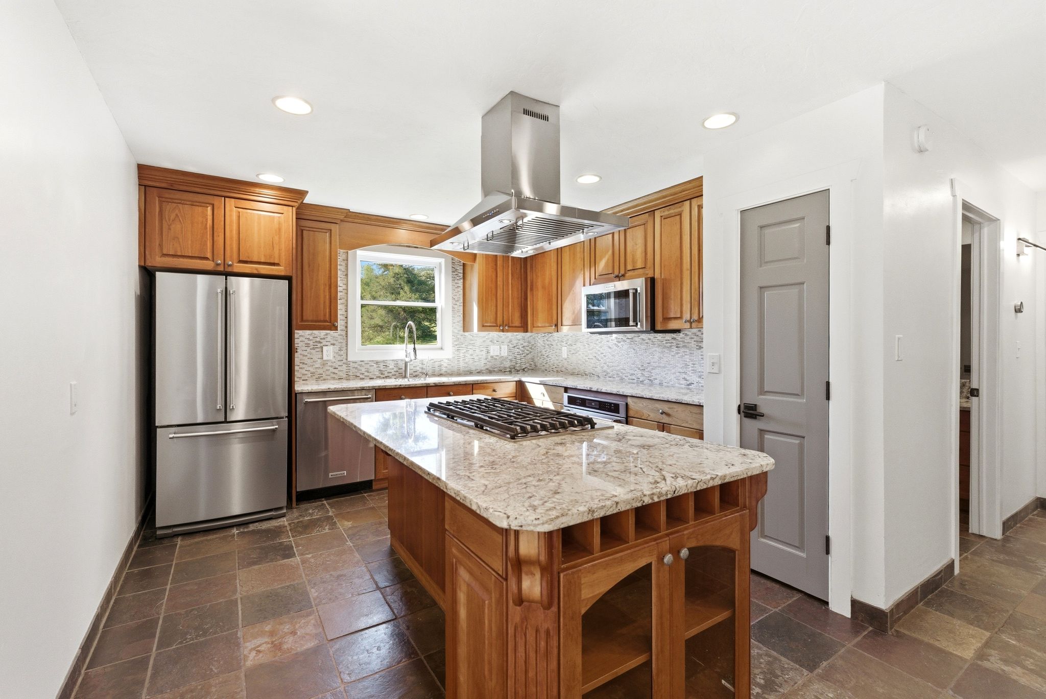 Kitchen featuring a center island with a gas cooktop, granite countertops, wood cabinetry, and stainless steel appliances