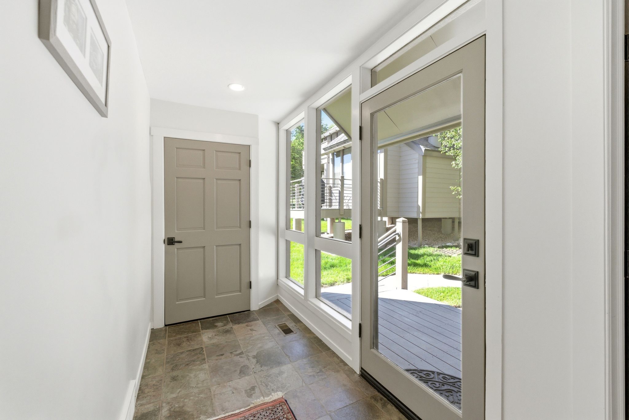 Entryway featuring large glass panel door, side windows, recessed lighting, and slate-look tile flooring