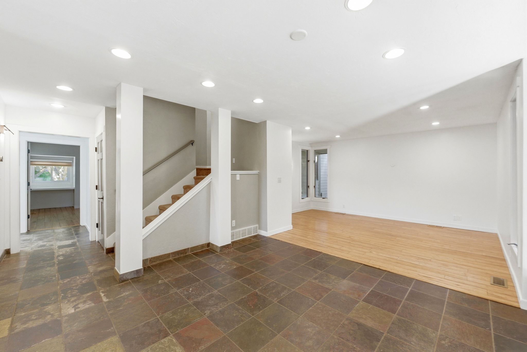 Spacious interior featuring a combination of natural stone tile flooring and wood-finish flooring