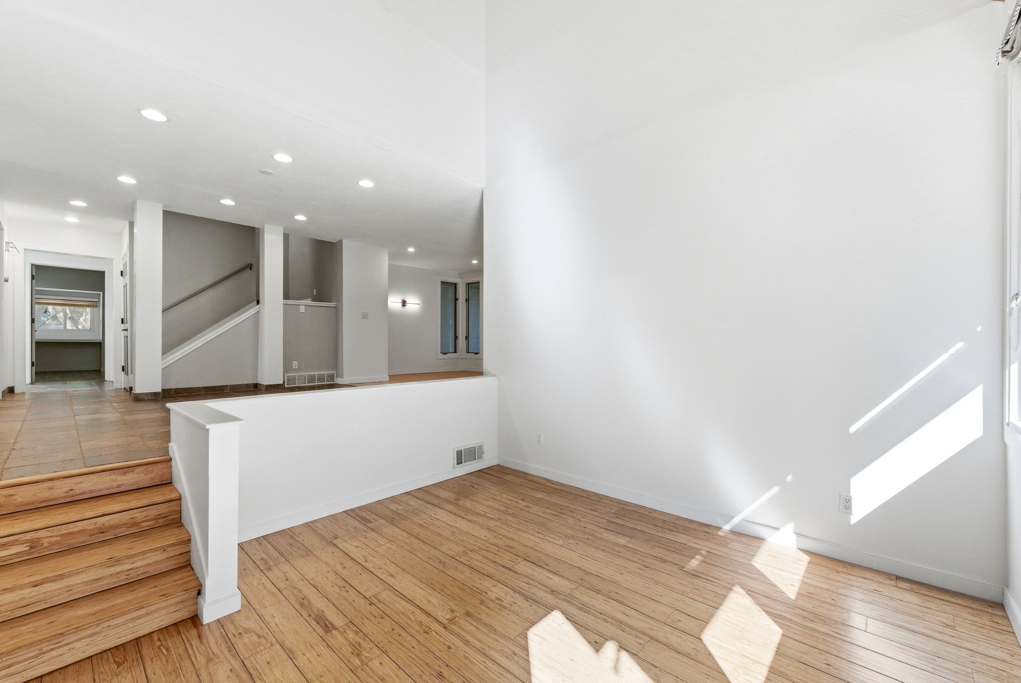 Living space featuring wood-finish flooring, high ceilings, and a half-wall partition