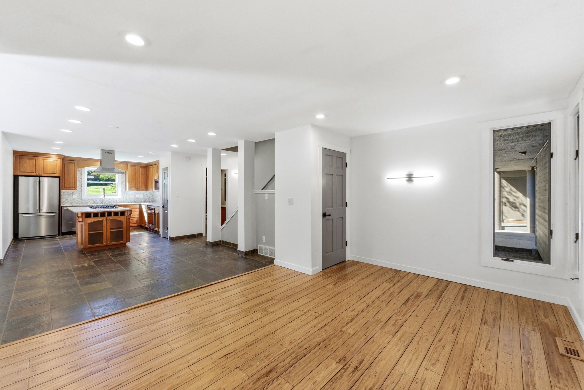 Open-concept living area with wood-finish flooring transitioning to large format tile