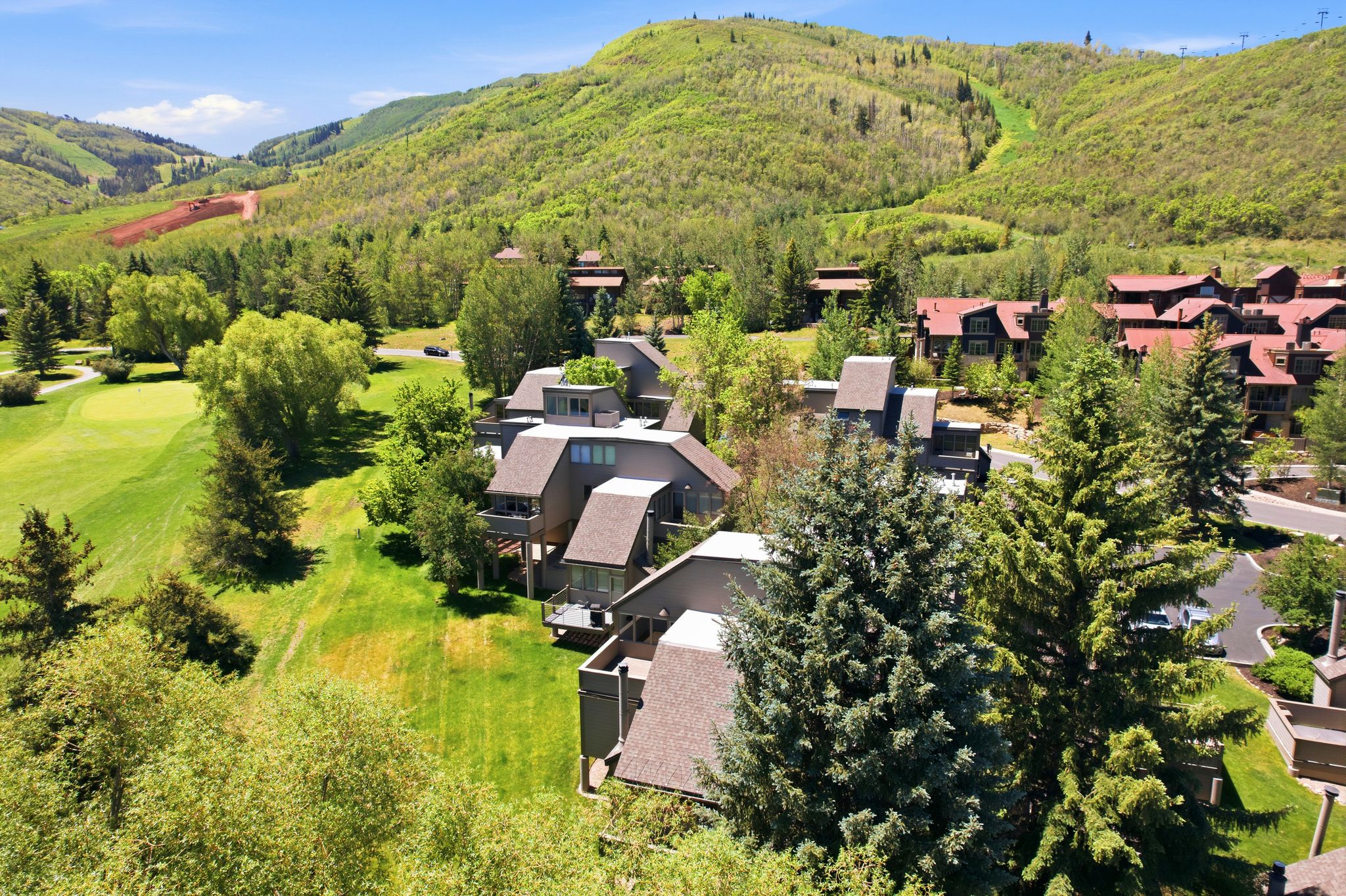 Contemporary multi-level residence with balconies, surrounded by mature trees and lush green landscaping