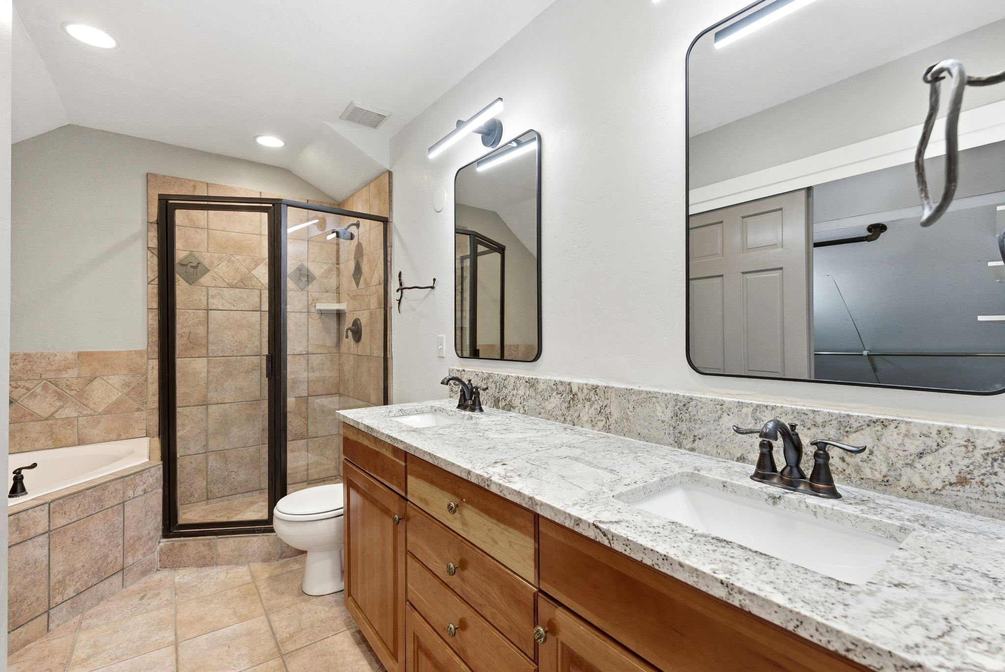Dual vanity with light-toned stone countertop, integrated sinks, and bronze-finish fixtures