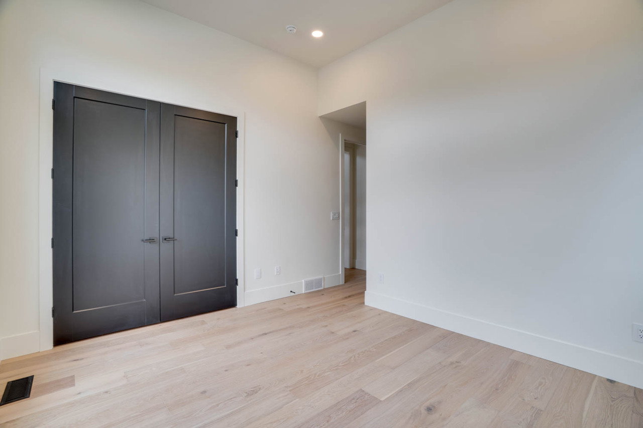 Double black doors with contrasting white trim, recessed lighting, and light wood-finish flooring
