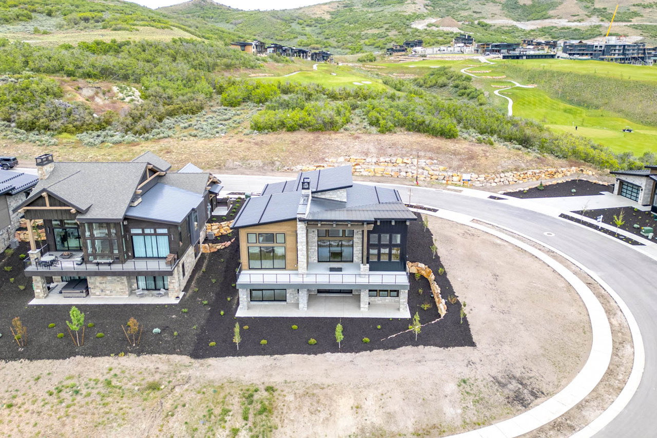 Modern mountain-style residence featuring a multi-level design, a prominent stone facade, and a flat black roof