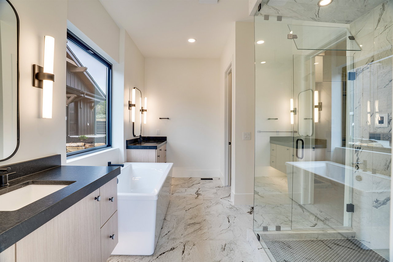 Spacious bathroom featuring a freestanding soaking tub, wood-finish vanity with dark countertops, and a large walk-in shower with glass enclosure