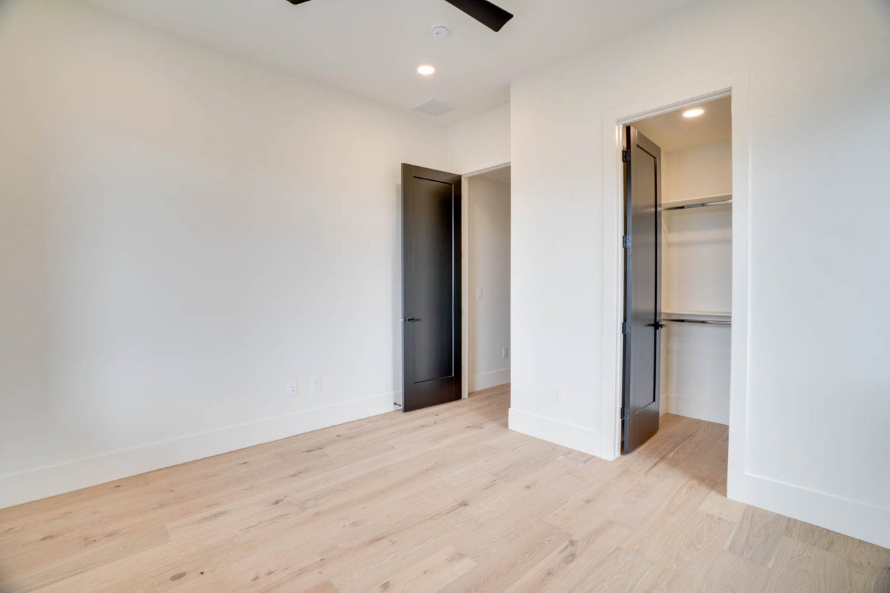 Bright interior space featuring light wood-finish flooring, white walls, and dark-paneled doors