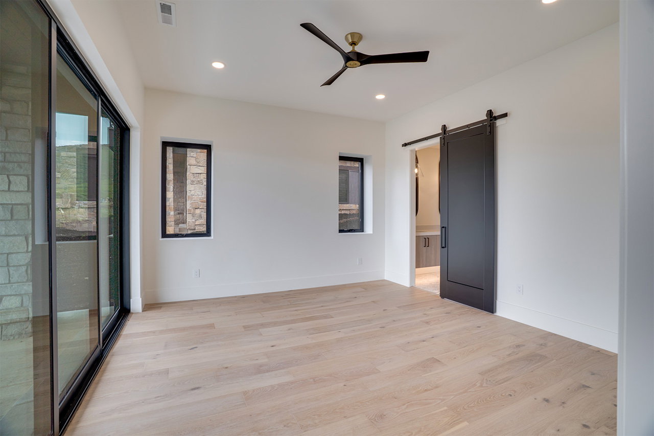 Spacious room with light wood-finish flooring, recessed lighting, and a modern ceiling fan