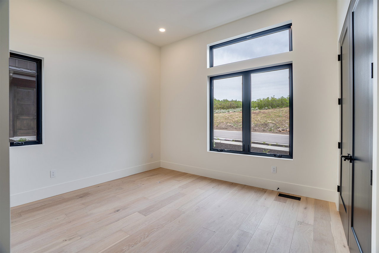 Light-filled room featuring a large transom window, a secondary black-framed window, recessed ceiling lighting, and light wood-finish flooring