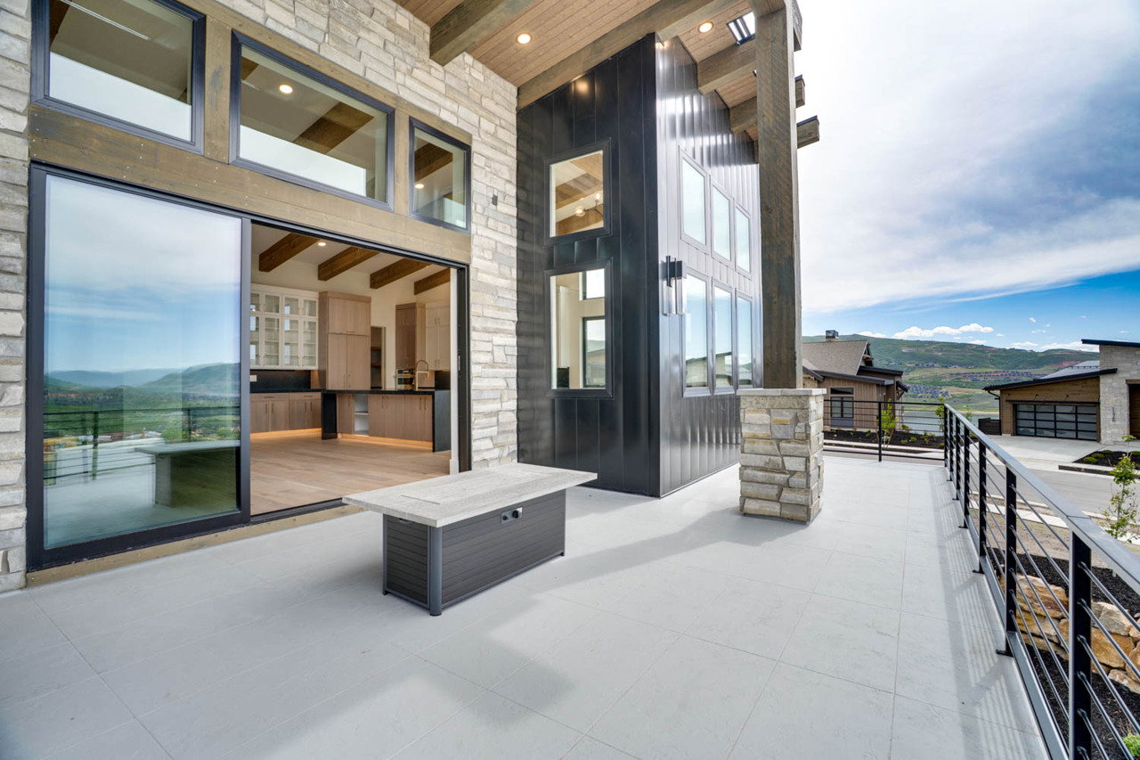 Expansive outdoor patio featuring light-toned tile flooring and a black metal railing