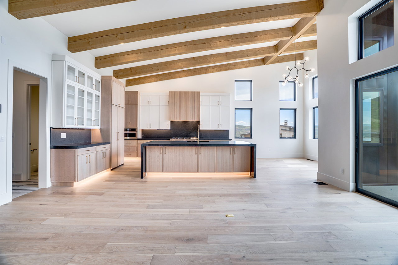 Open-concept living space with a vaulted ceiling featuring exposed wood beams