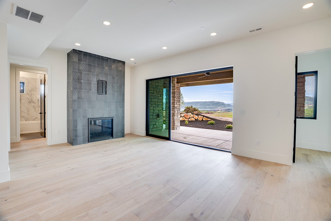 Spacious interior featuring wide plank wood-finish flooring and a contemporary fireplace with dark tile surround