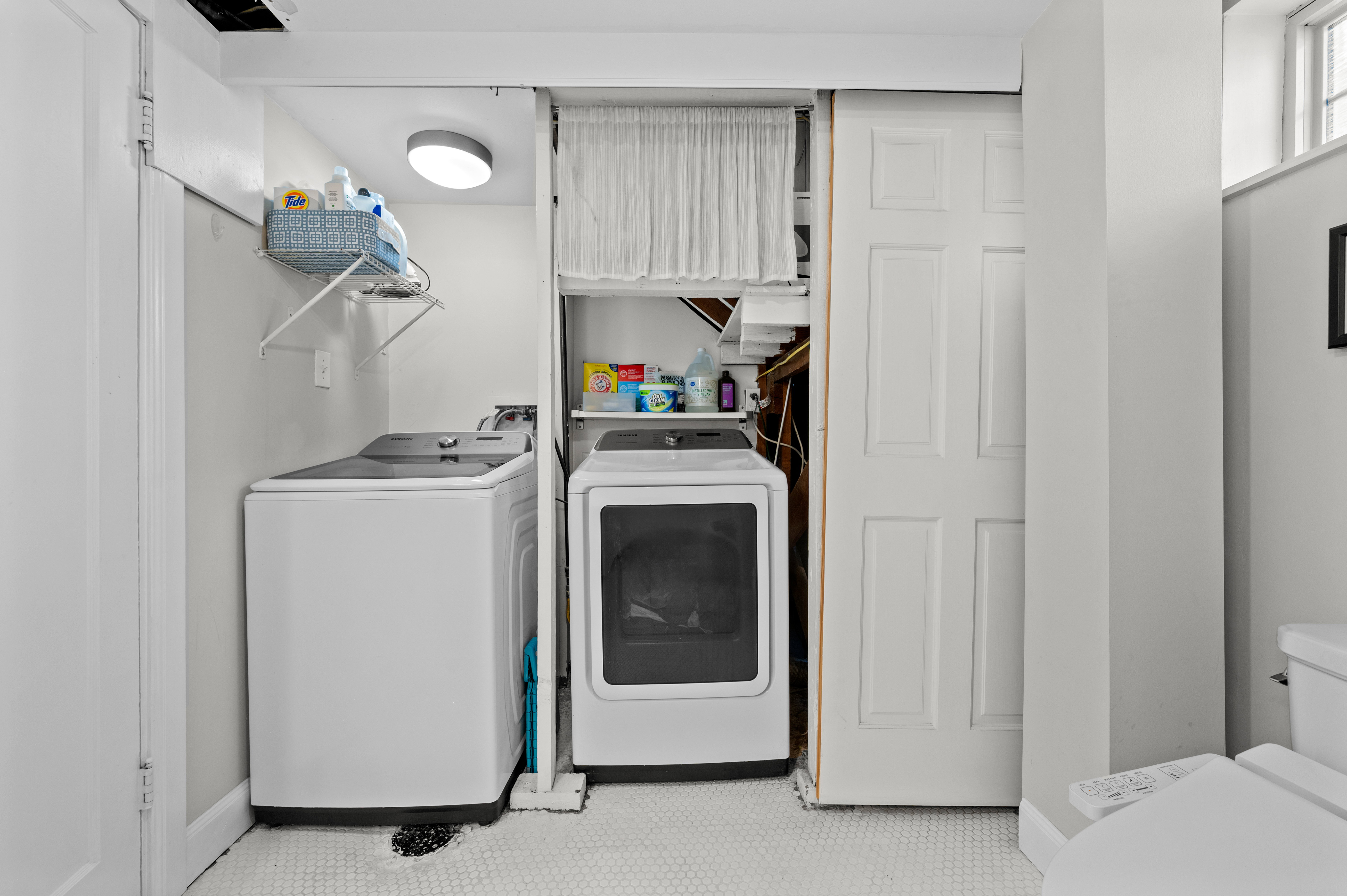 Dedicated laundry area featuring a top-load washing machine, front-load dryer, and overhead shelving for storage