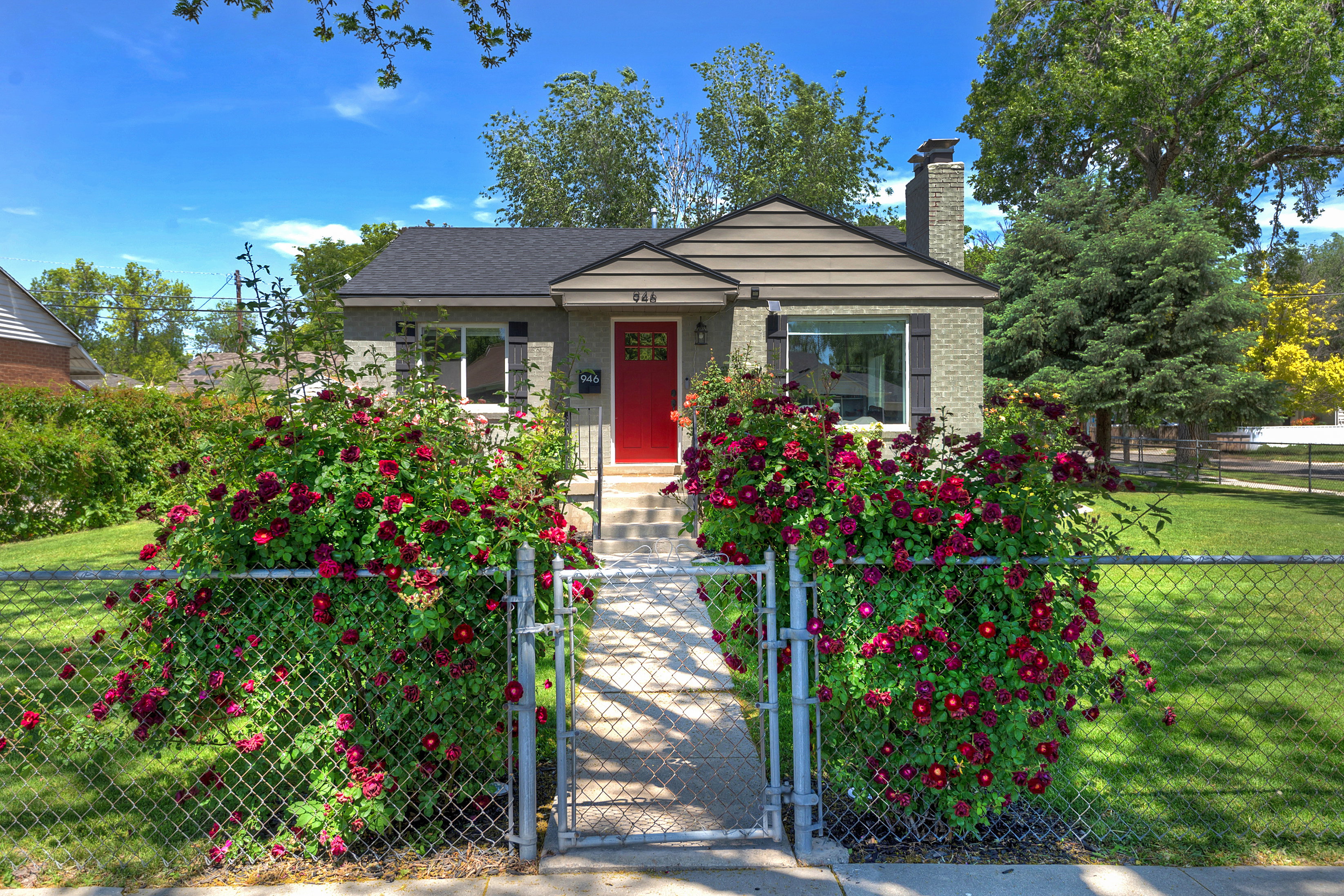 Charming bungalow-style residence featuring a red front door, light-toned brick facade, and a prominent brick chimney