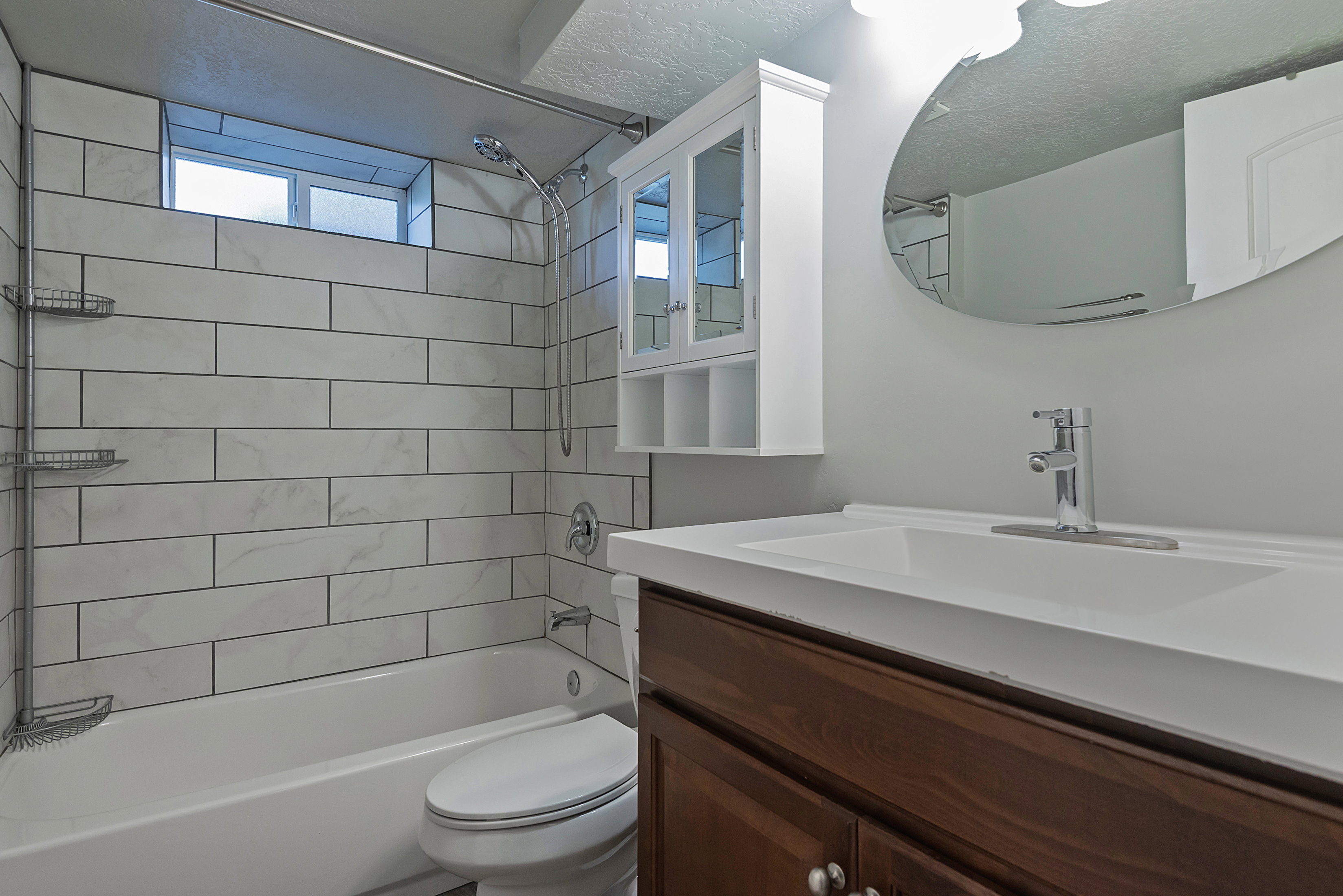 Bathroom featuring a white subway tile shower surround with dark grout, a built-in tub, and a chrome shower head
