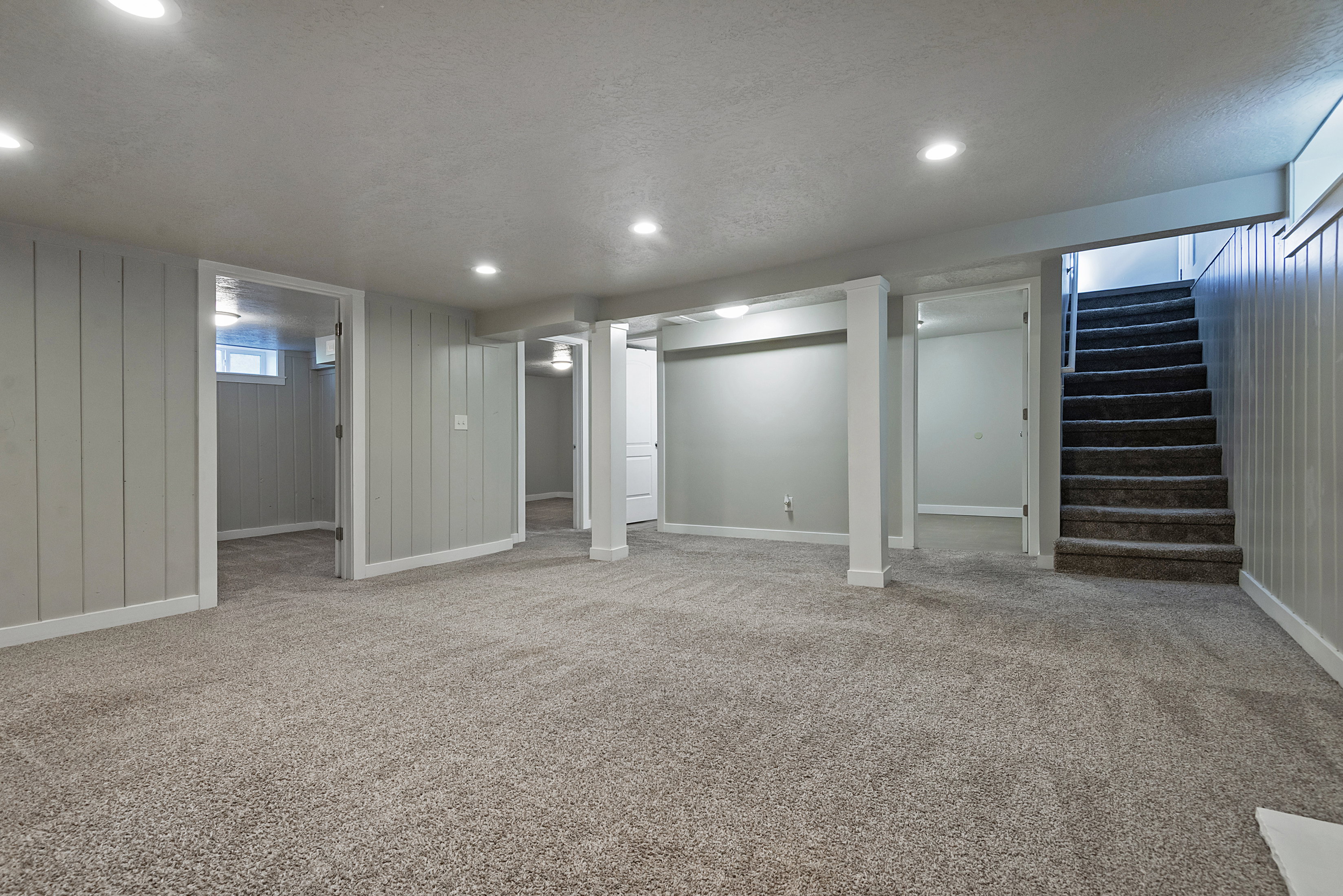 Spacious lower level featuring neutral carpeting, recessed lighting, white trim, and light gray walls with vertical paneling