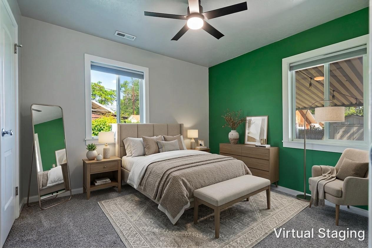 Spacious bedroom featuring a prominent green accent wall, two large windows, a ceiling fan with integrated lighting, and plush carpet flooring