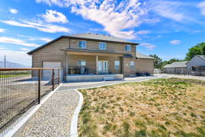 Two-story residence featuring light brown siding, a covered patio, and a gravel pathway