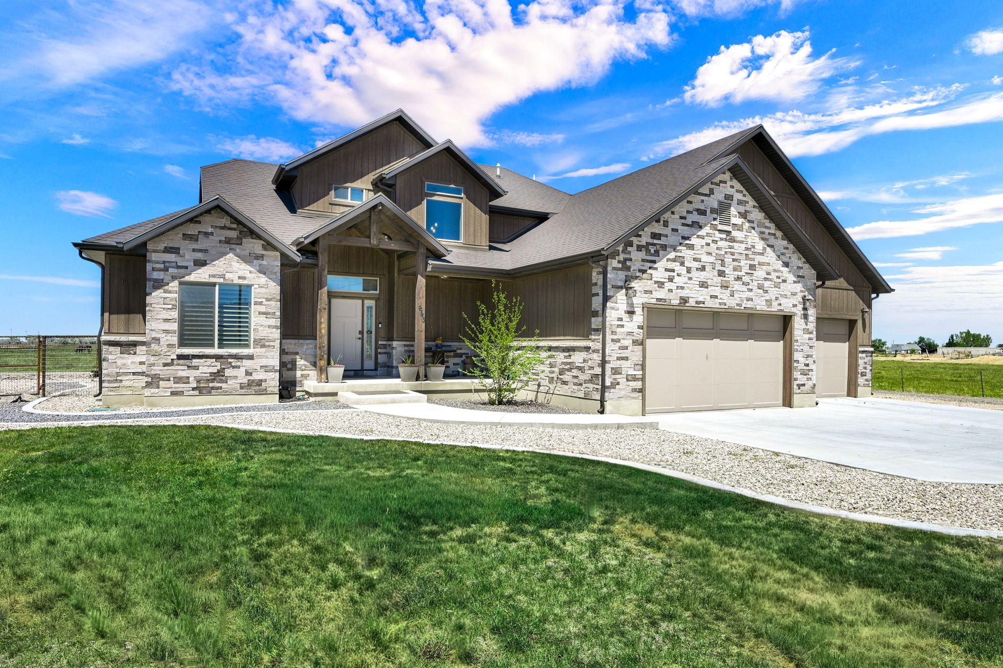 Contemporary residence featuring a multi-tone stone facade, a covered entry with timber accents, and a dual garage