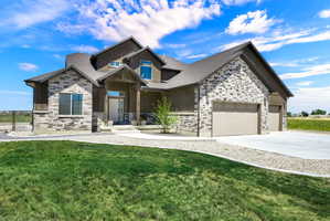 Contemporary residence featuring a multi-tone stone facade, a covered entry with timber accents, and a dual garage