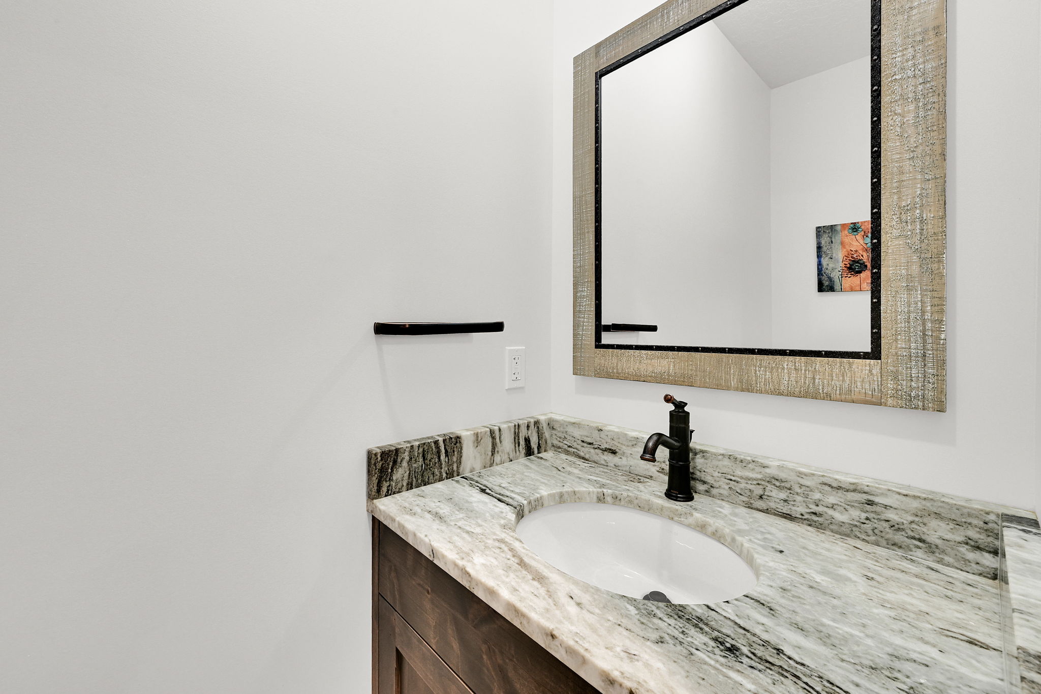 Vanity featuring a white oval undermount sink, a dark bronze faucet, and a stone countertop with natural veining