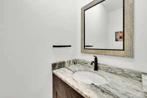 Vanity featuring a white oval undermount sink, a dark bronze faucet, and a stone countertop with natural veining