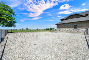 Expansive gravel outdoor area featuring a modern two-story exterior with vertical siding and a stone accent facade