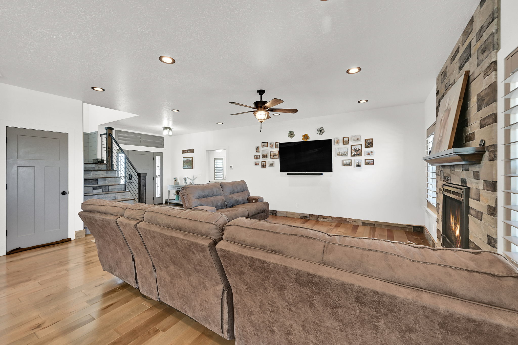 Living area featuring a floor-to-ceiling stone fireplace with mantel, recessed lighting, and wood-finish flooring