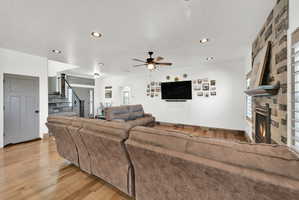 Living area featuring a floor-to-ceiling stone fireplace with mantel, recessed lighting, and wood-finish flooring
