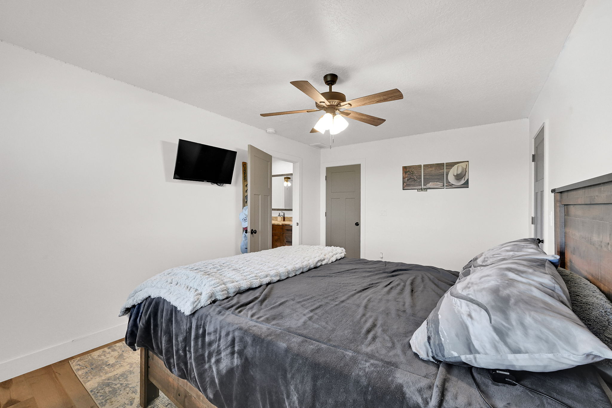 Bedroom featuring wood-finish flooring, a ceiling fan with integrated lighting, and white walls