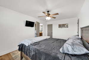 Bedroom featuring wood-finish flooring, a ceiling fan with integrated lighting, and white walls
