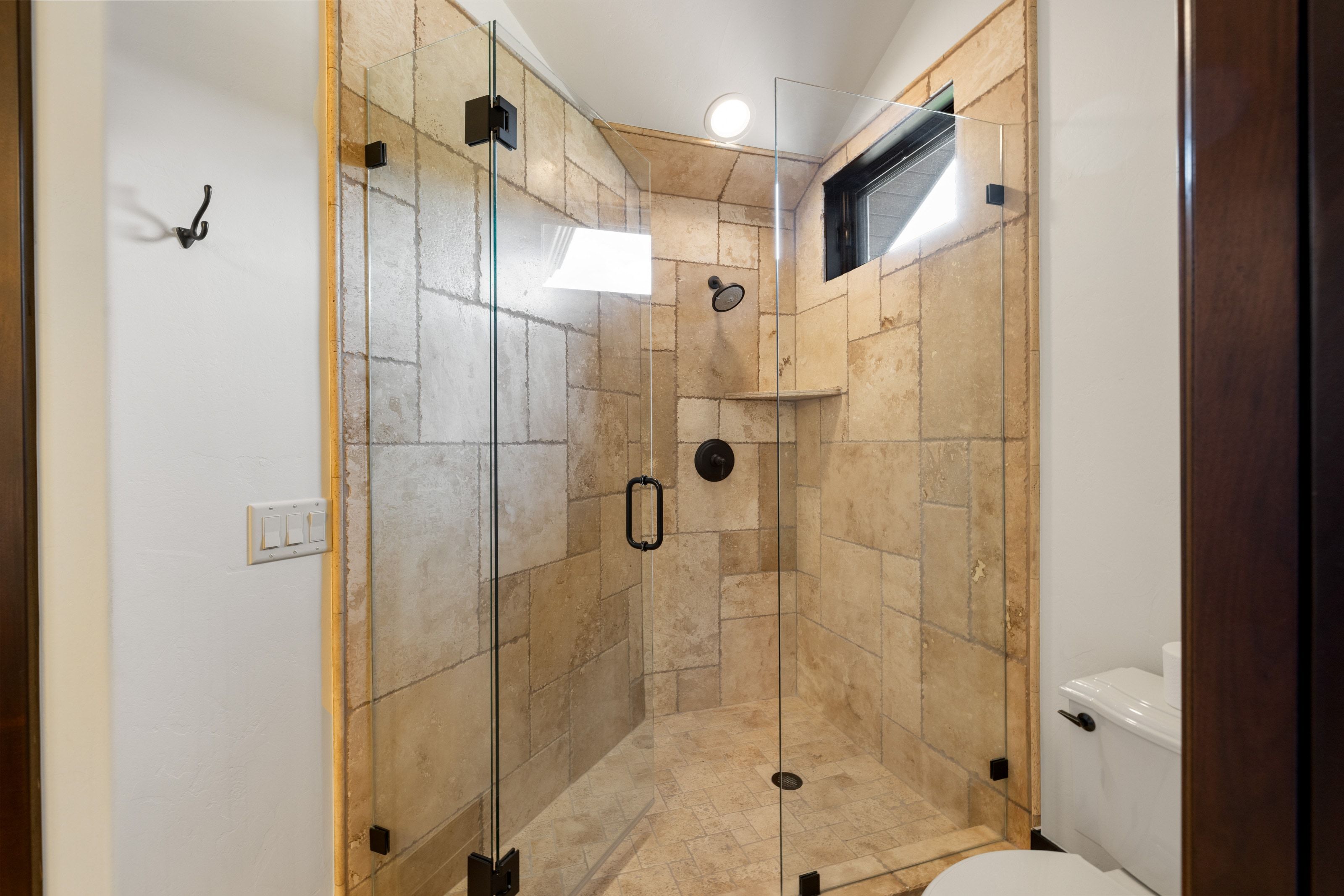 Glass-enclosed shower featuring large format tile, a built-in shower niche, and matte black fixtures