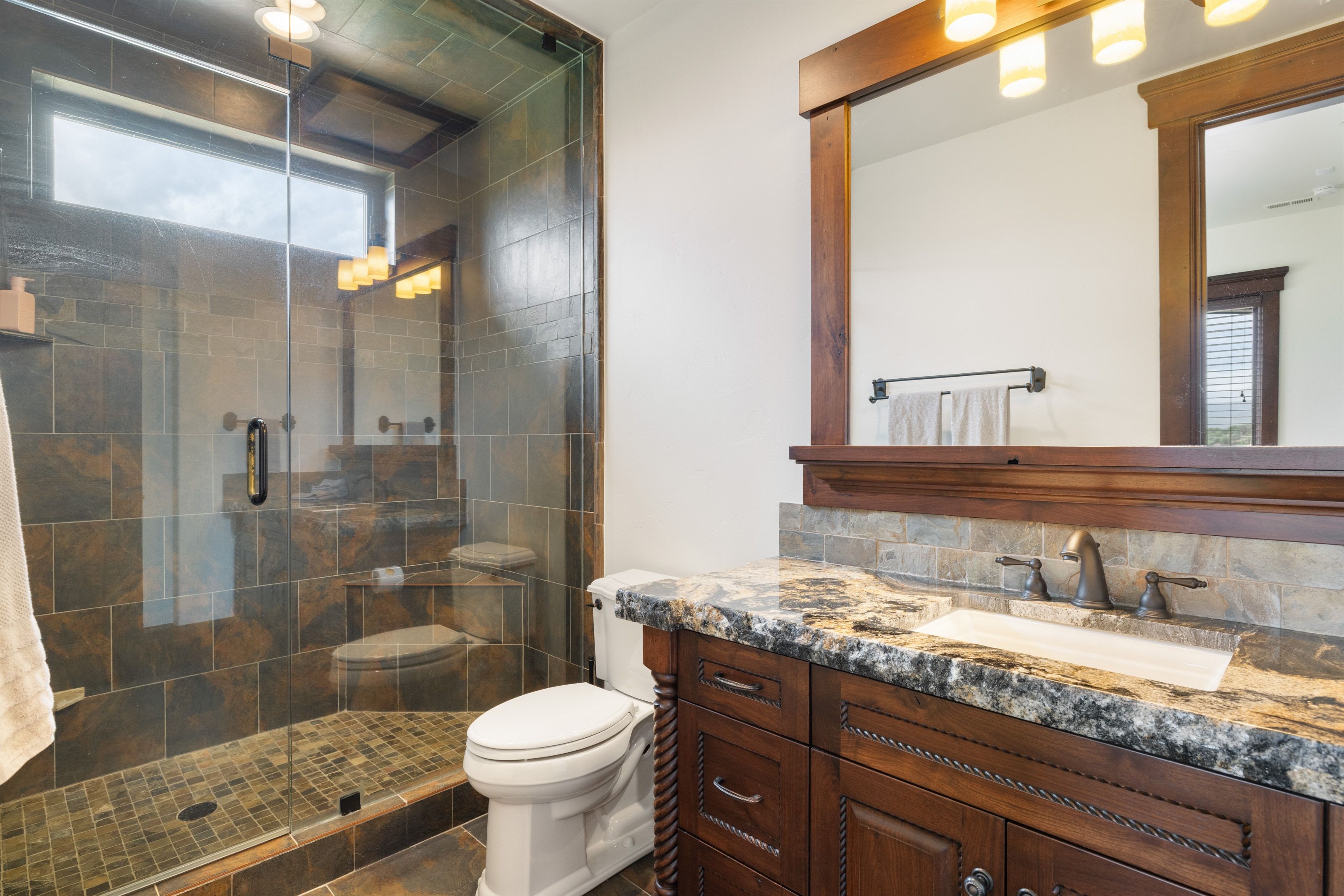 Bathroom featuring a frameless glass shower enclosure with tile surround and a transom window
