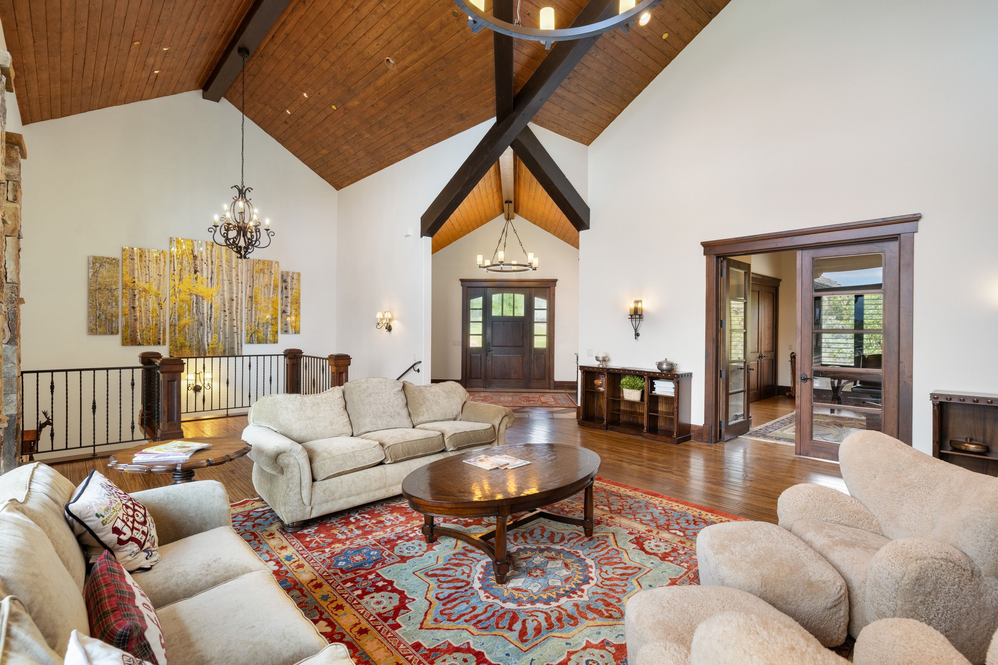 Spacious living area featuring vaulted wood-paneled ceilings, exposed wood beams, and hardwood flooring