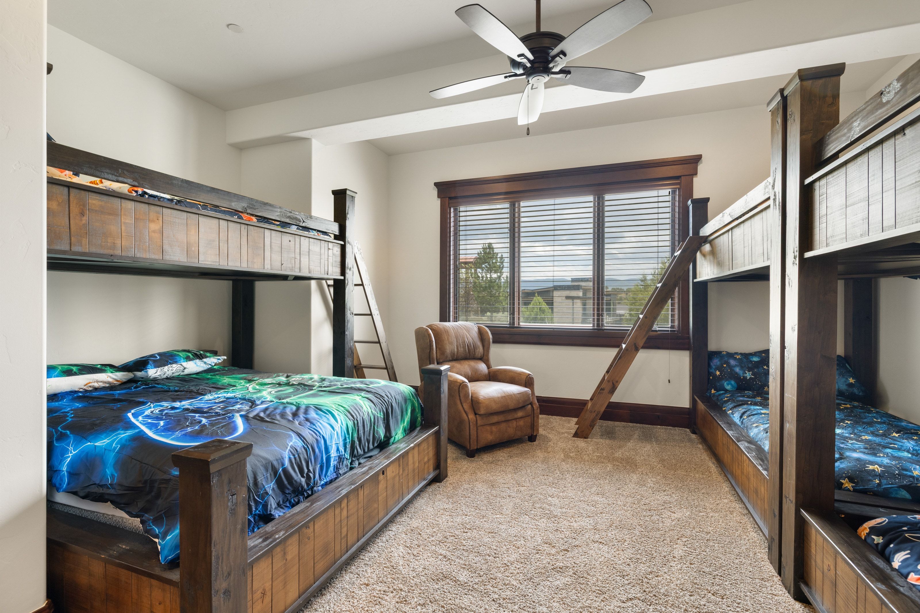 Carpeted room featuring a large window with horizontal blinds, a ceiling fan with integrated lighting, and white walls