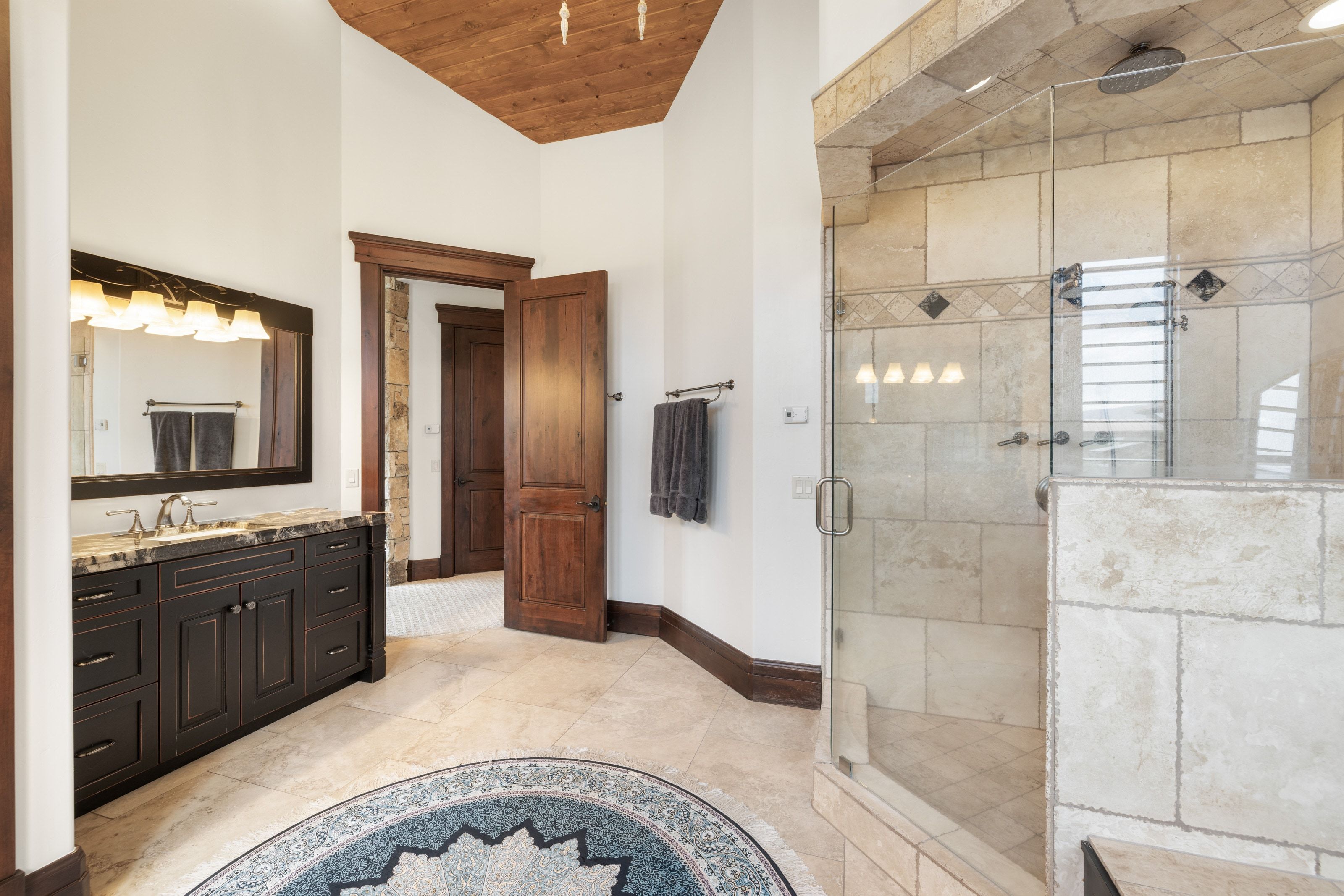 Spacious bathroom featuring a large glass-enclosed shower with stone tiling and a rain showerhead