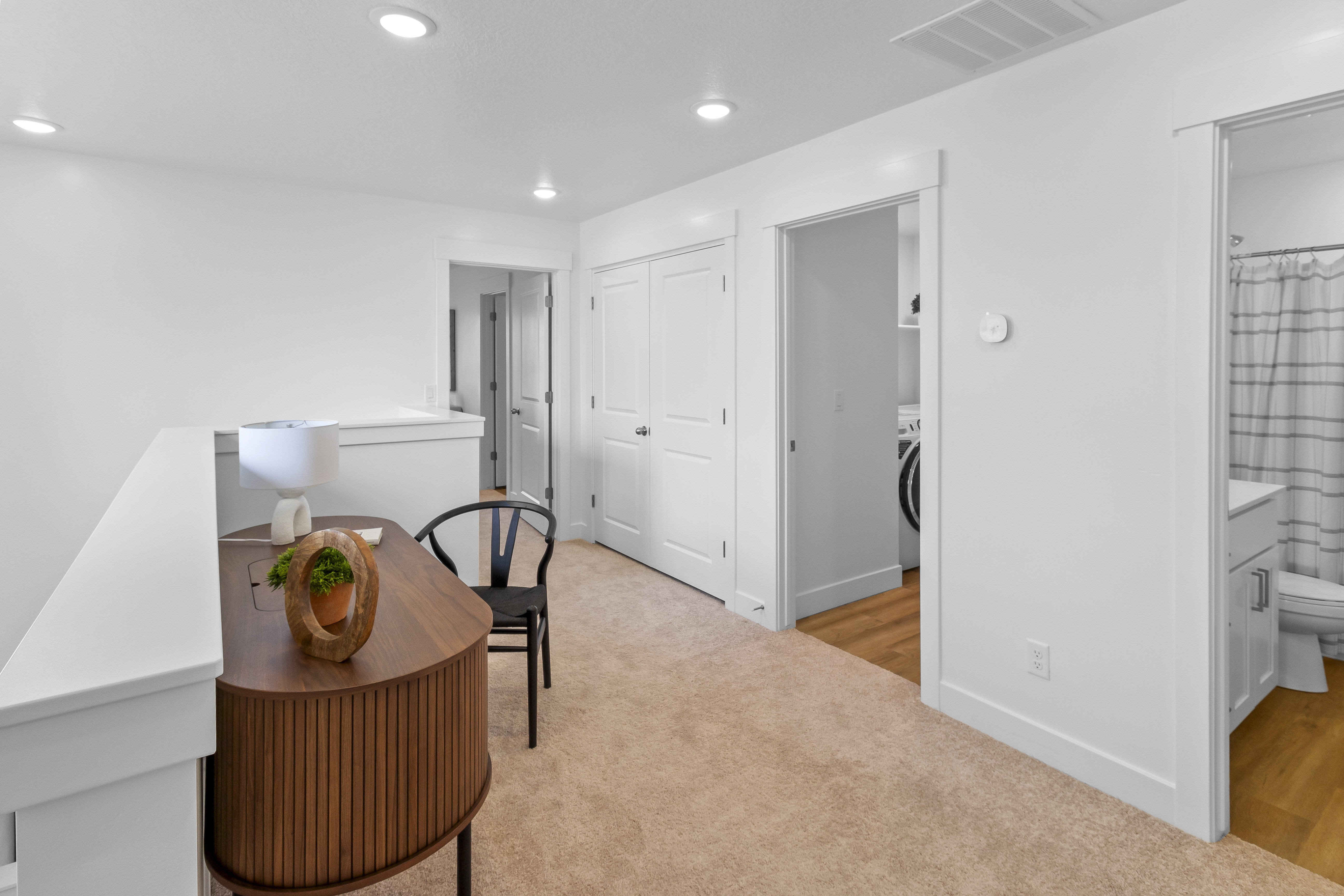 Carpeted hallway with white walls and recessed lighting