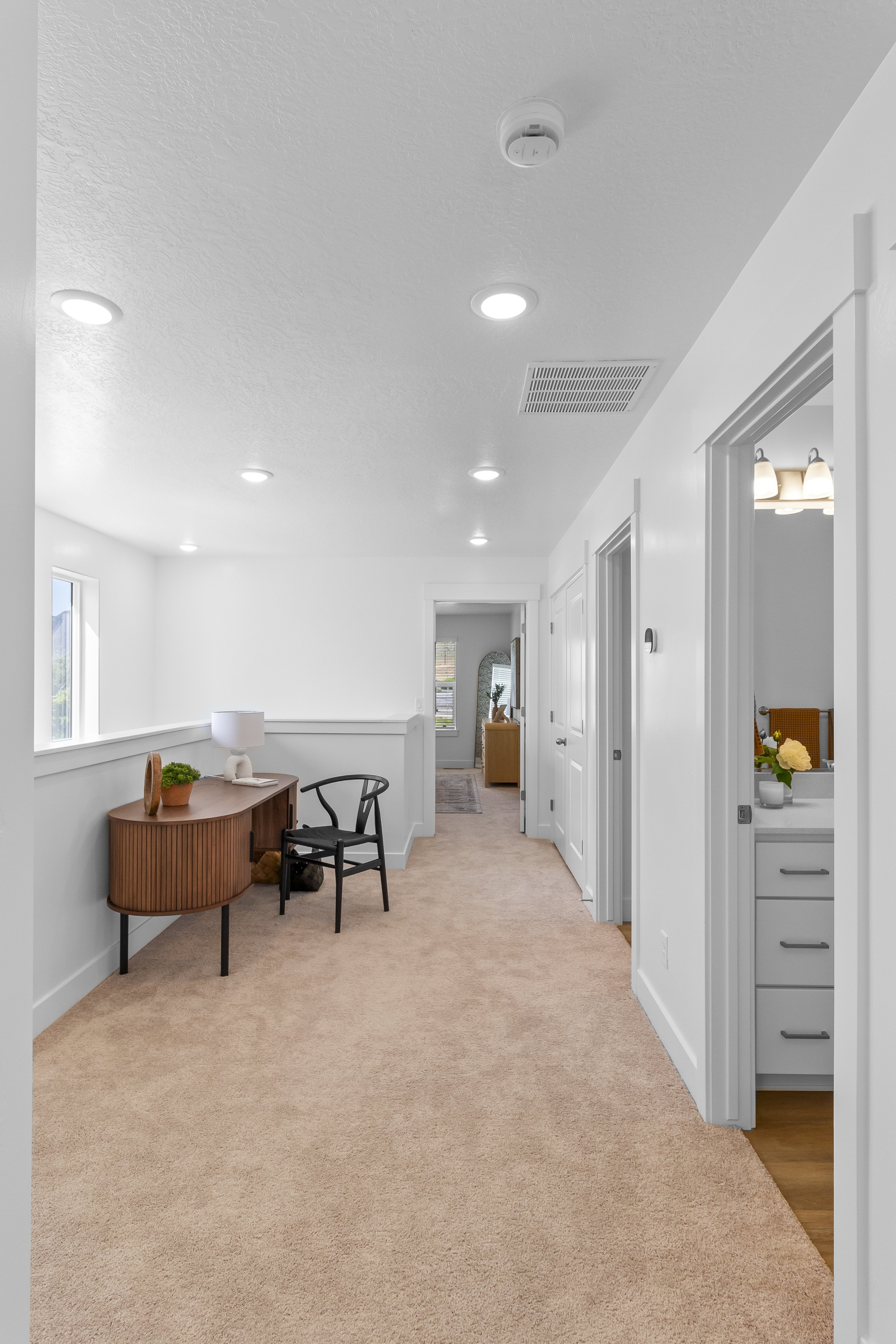 Upper-level hallway with neutral carpeting and recessed lighting