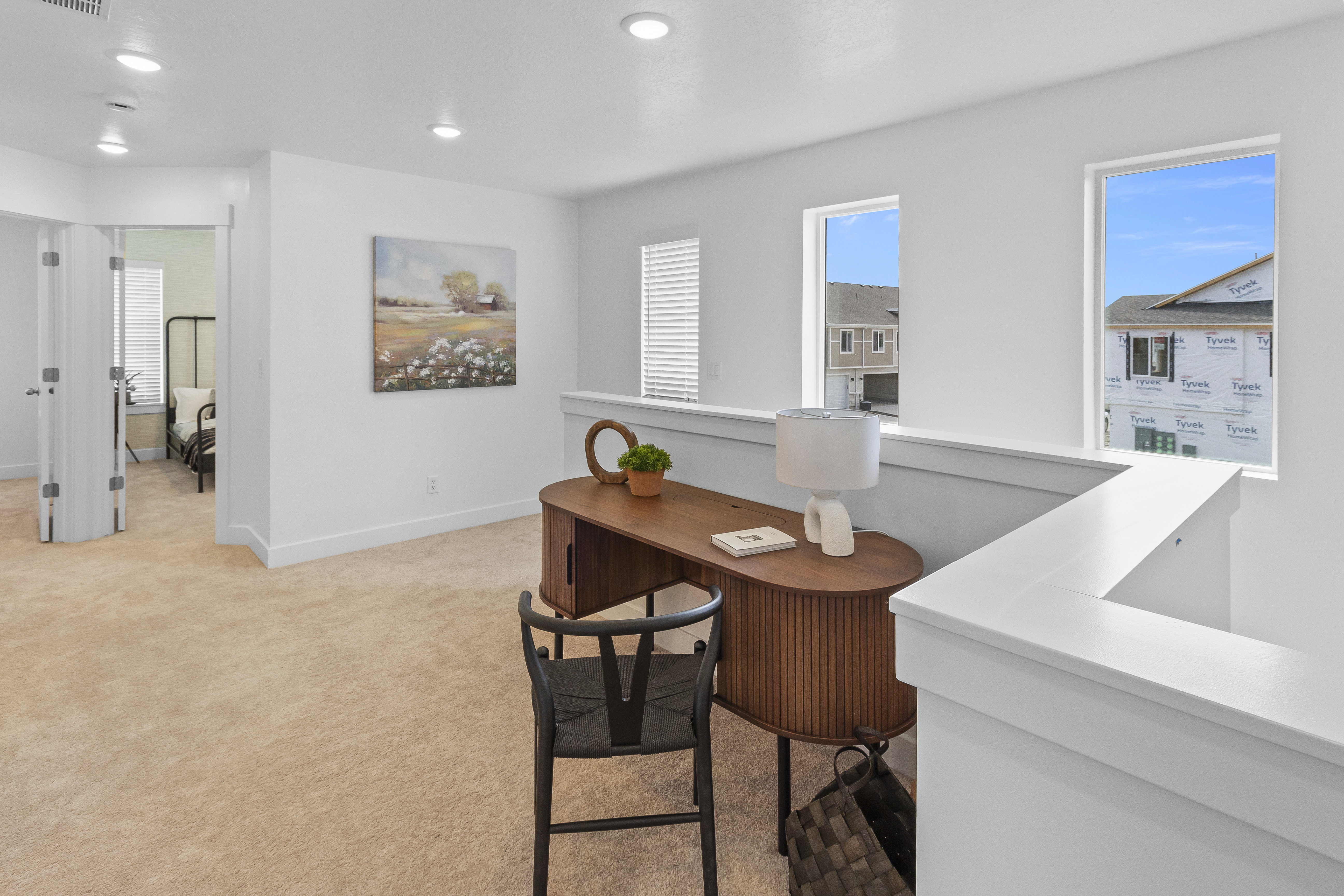 Carpeted loft area featuring white walls, recessed lighting, and a white balustrade