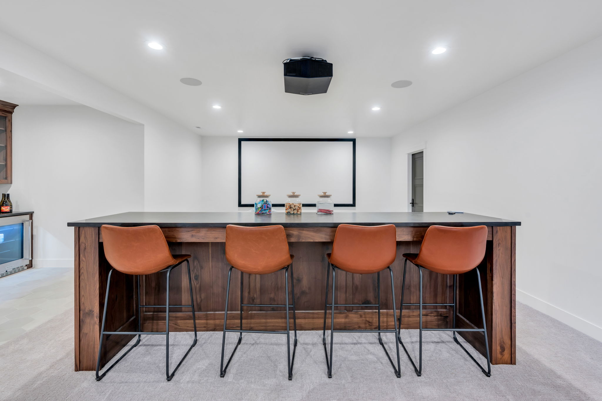 Built-in wood-finish bar with a dark countertop and four bar stools