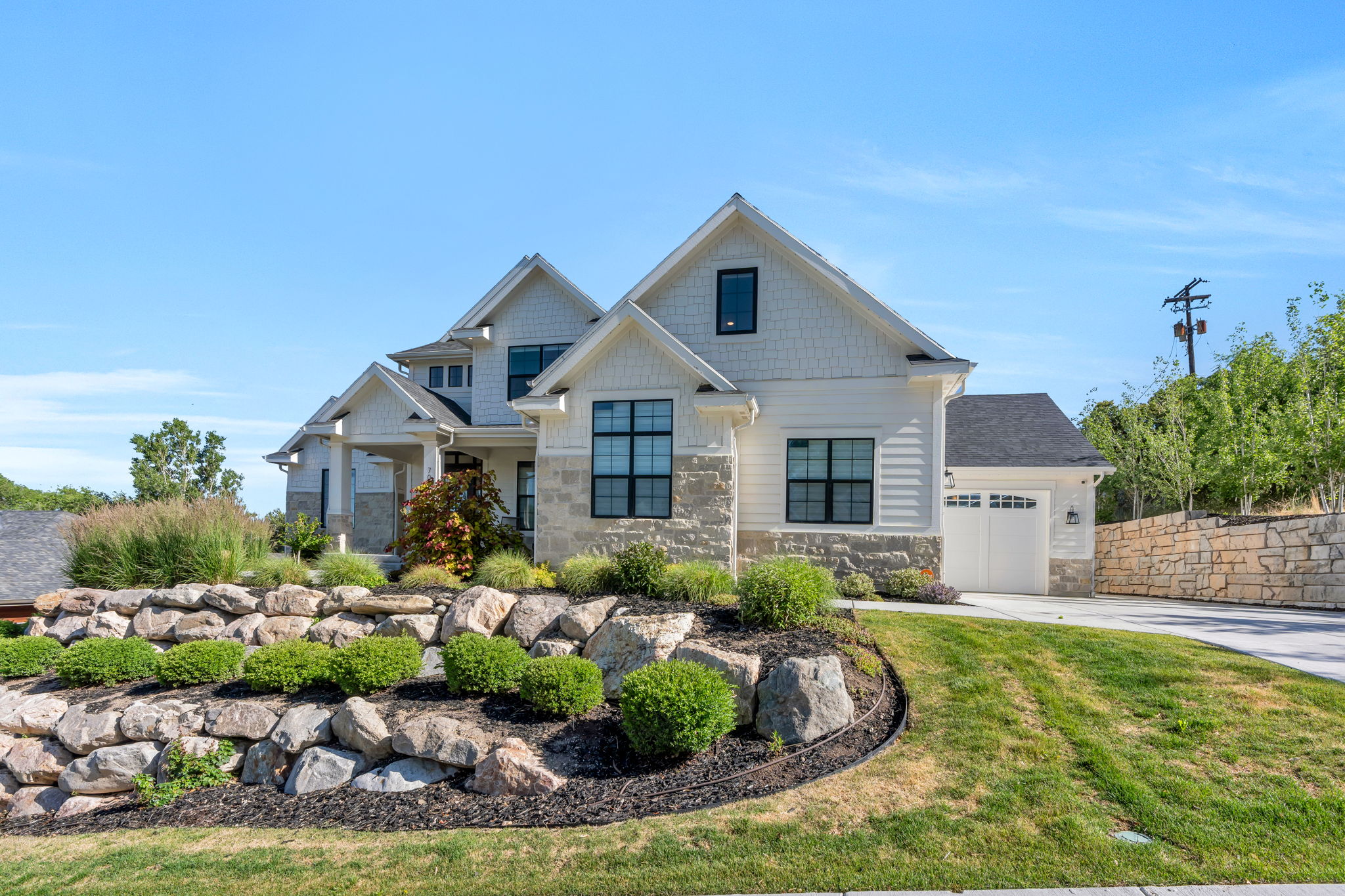 Multi-level residence featuring a stone and shingle facade, prominent gables, and dark-framed windows