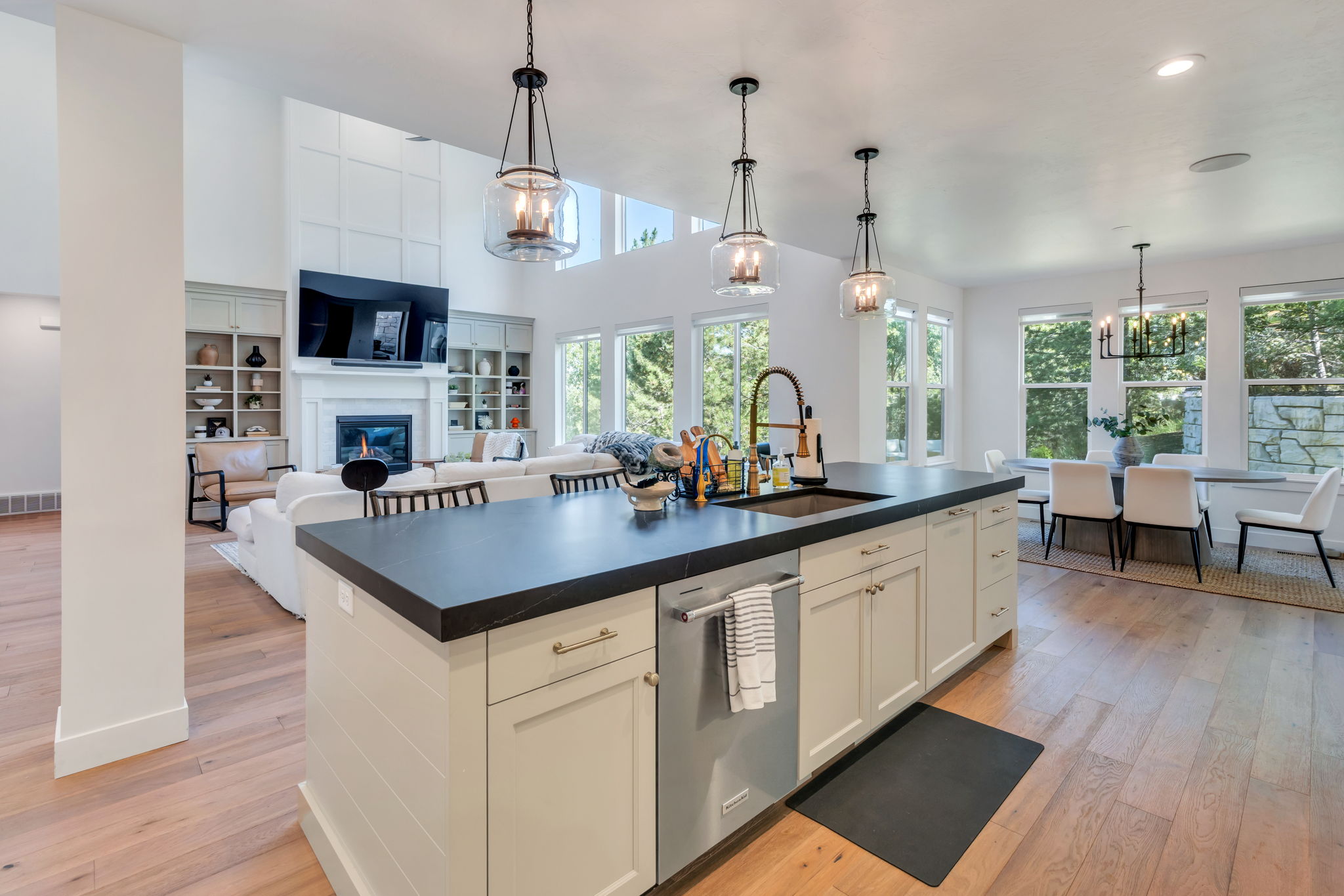 Kitchen island featuring a dark countertop, integrated sink with a gooseneck faucet, and light-toned cabinetry
