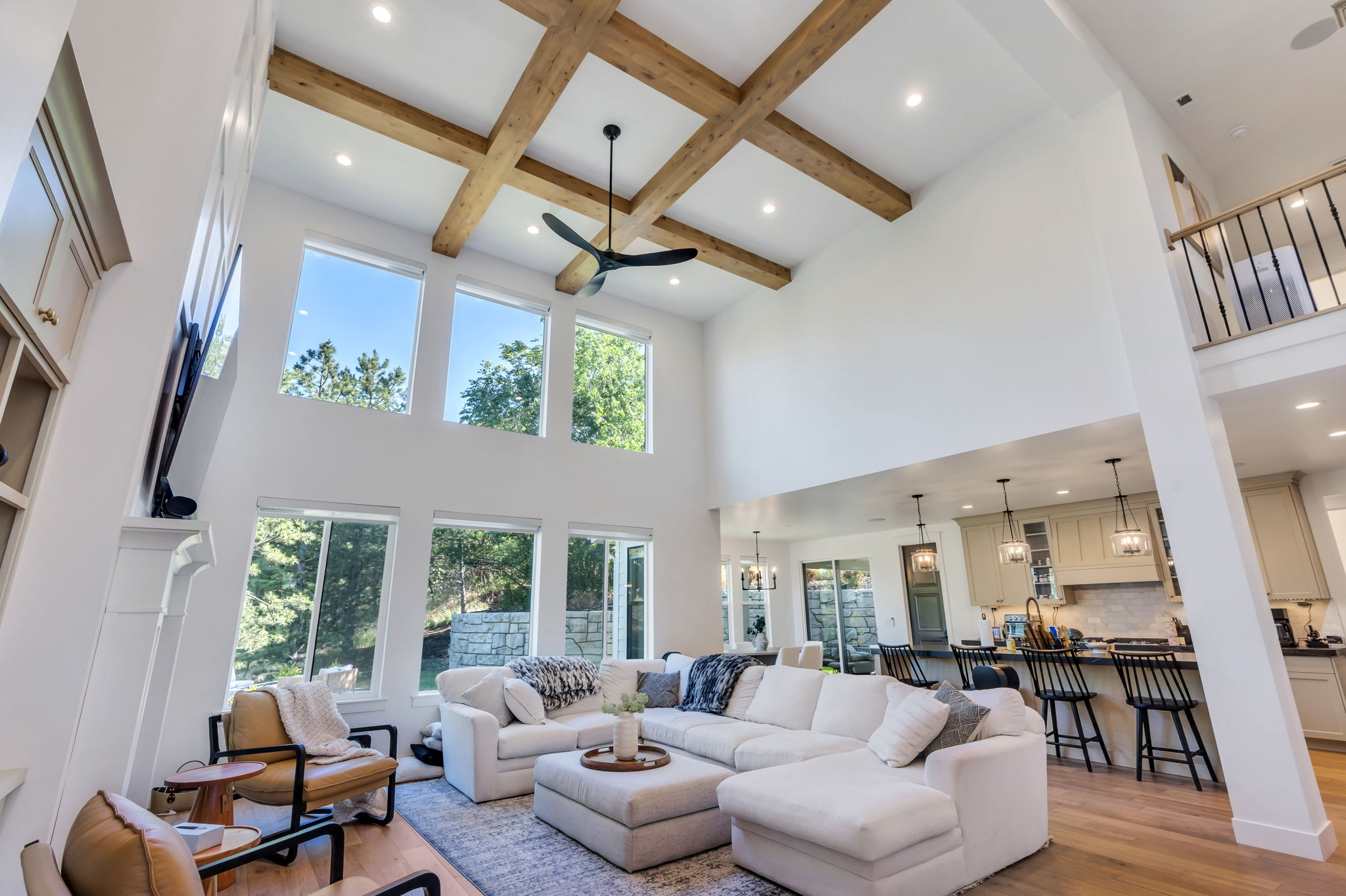 Two-story living area featuring a coffered ceiling with wood beams, a contemporary ceiling fan, recessed lighting, and a wall of windows