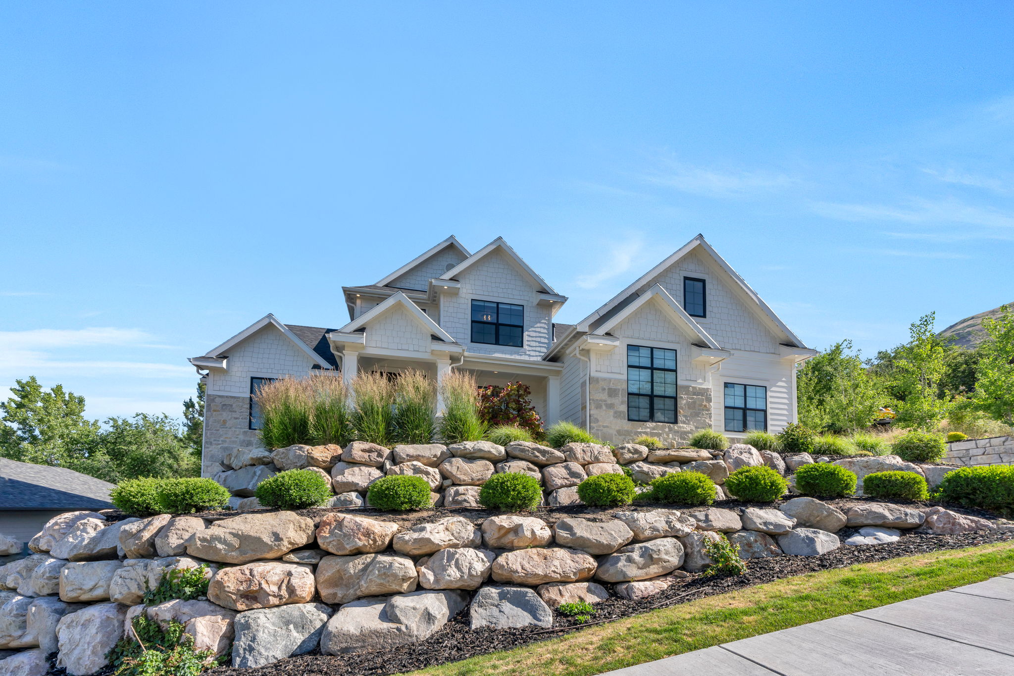 Contemporary residence featuring multiple gables, white siding, and stone accents