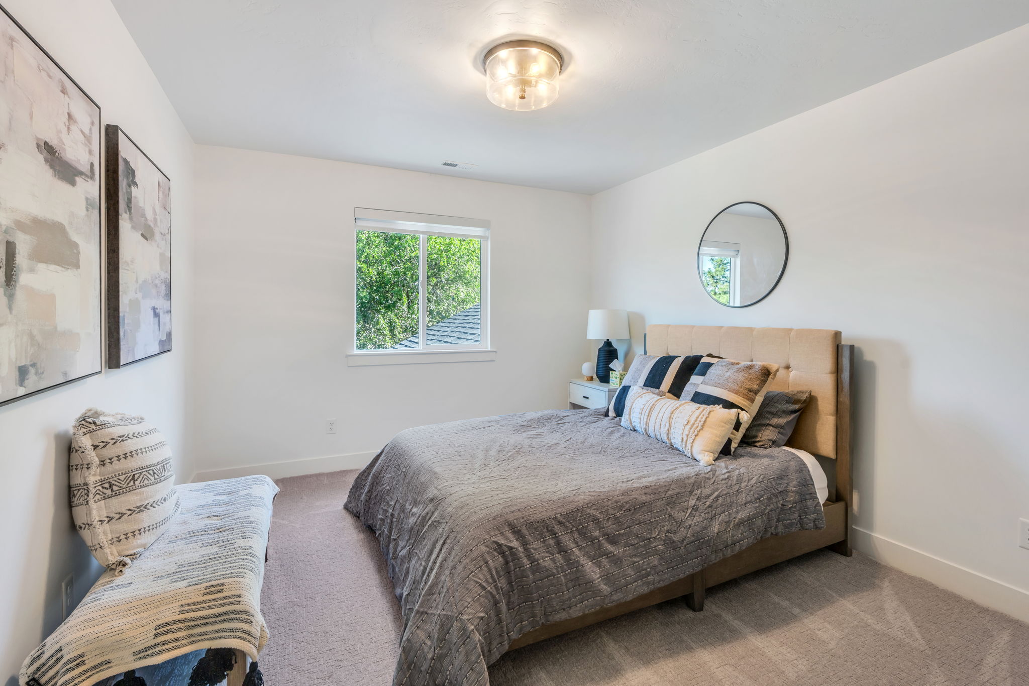 Carpeted room featuring a single window with outdoor greenery, a semi-flush mount ceiling light, and white painted walls