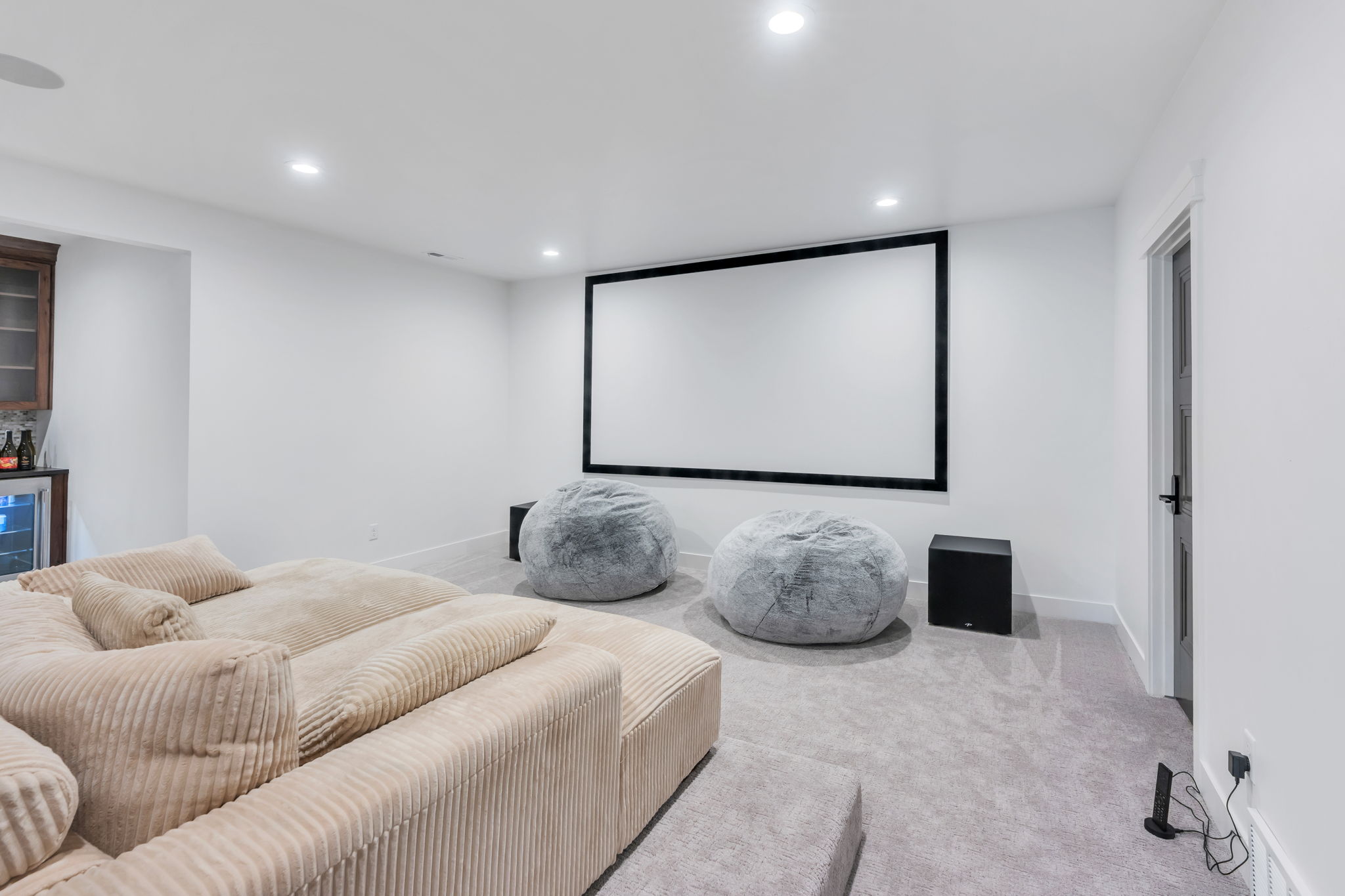 Dedicated media room featuring a large projection screen, recessed lighting, and soft gray carpeting